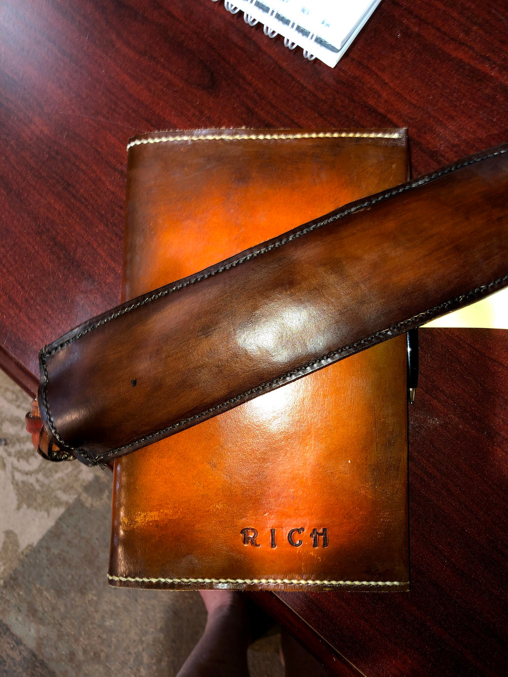 Personalized leather cover with contrasting stitching and a warm brown finish.